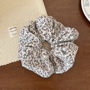 Gros plan d'un chouchou géant en tissu fleuri avec motif noir sur une table en bois