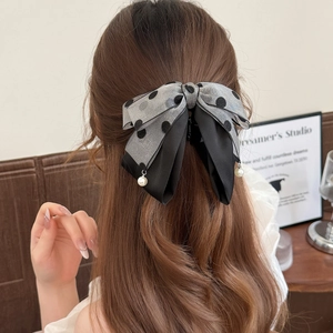 Elegant grey polka dot bow hair clip with pearl pendant worn on long wavy hair