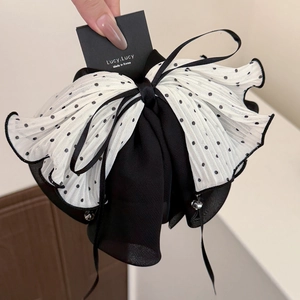 Détail d'un nœud à cheveux en mesh multicouche avec pois noirs et pendentif argenté