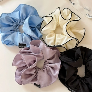 Primo piano di quattro elastici per capelli in raso pieghettato in blu, bianco e nero