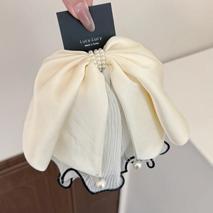 Detail of elegant cream satin bow hair claw with pearls and wave pattern mesh trim