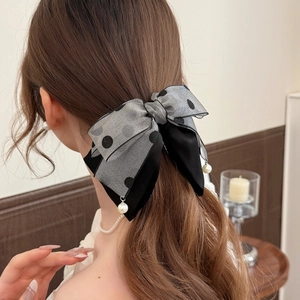 Detail showing grey polka dot bow hair clip with pearl pendants and mesh texture