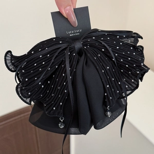 Détail de la pince à cheveux en mousseline noire plissée à pois avec longs rubans