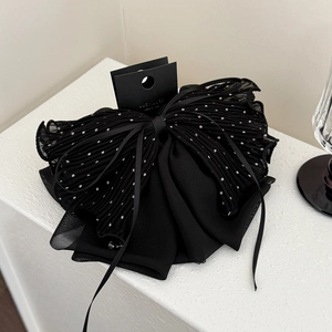 Détail de la pince à cheveux en tulle à pois noirs avec nœud plissé et rubans en mousseline