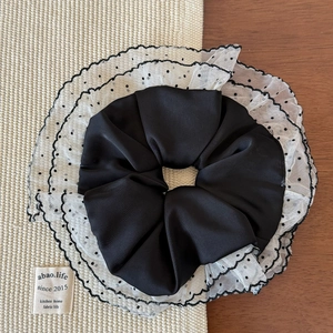 Macro view of double-layered pleated lace scrunchie with polka dots and ruffled mesh edge
