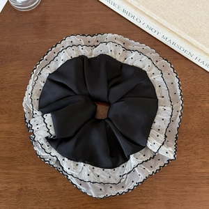 Black and white polka dot mesh layered lace scrunchie on a vintage wooden desk
