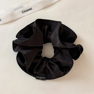Dettaglio di un elastico grande in raso nero con etichetta di testo per uno styling elegante