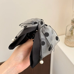 Detail of grey polka dot bow hair claw with elegant pearl pendants and mesh fabric