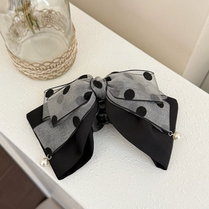 Detailed view of gray polka dot bow hair clip with white pearl charms and mesh texture