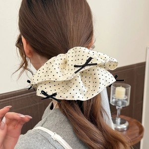 Elegant cream oversized polka dot scrunchie with black bows shown on model hairstyle