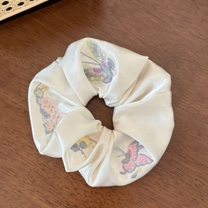 Vue détaillée du chouchou en soie crème avec des motifs de papillons brodés élégants