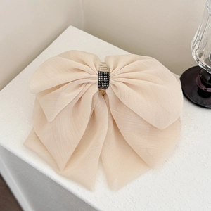 Close-up of a large beige mesh bow hair claw clip with a black rhinestone center band