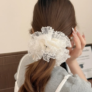 Nahaufnahme eines weißen Oversize-Spitzen-Scrunchies mit Punkt-Netzgewebe am Pferdeschwanz