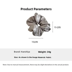 Detailed view of grey satin scrunchie showing 15cm diameter size and glossy fabric texture