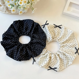 Polka dot scrunchies with pearl and bow details shown in a lifestyle flat lay