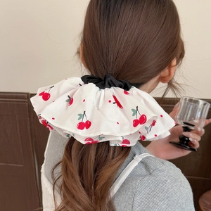 Floral scrunchie with red cherry print on white fabric shown on a ponytail