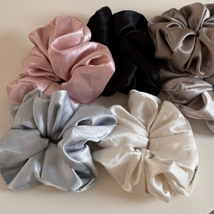 Close-up of assorted glossy satin scrunchies in pink, black, and champagne colors