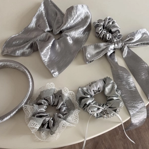 Flat lay of five-piece silver metallic fabric hair accessories with lace and bow details