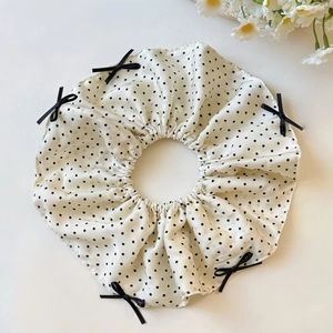 Detailed view of oversized white polka dot scrunchie with black ribbon bows