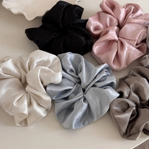 Detail shot of five large satin scrunchies in pastel tones with glossy pearl finish