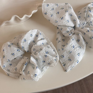 Detailed shot of white scrunchie with blue floral pattern and delicate lace trim edges