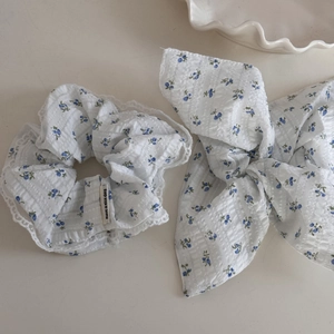 Close-up of blue floral scrunchie and bow hair tie with lace trim on white fabric