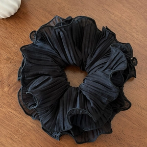 Vue détaillée d'un chouchou en tulle noir plissé posé sur un fond en bois sombre