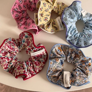 Détail de cinq chouchous floraux avec étiquettes fait main sur fond beige