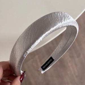 Detail of silver pleated fabric headband with a handmade label on the inner side