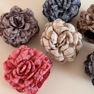 Detailed macro view of British plaid fabric rose hair clips in multiple classic colors