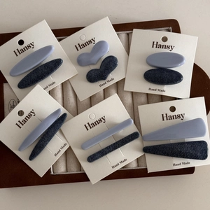 Denim blue and light blue patchwork hair clip set displayed in a wooden jewelry tray