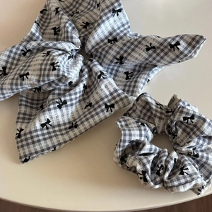 Vue détaillée des chouchous à motif vichy avec imprimés nœuds noirs sur tissu blanc
