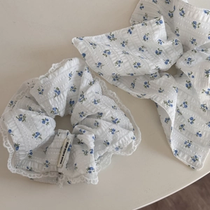 Close-up of blue floral scrunchie and headband set with lace trim and cotton texture