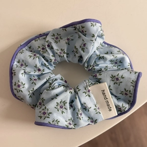 Détail de chouchou fleuri avec bordure violette et étiquette en tissu fait main
