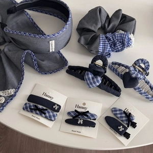 Flat lay of blue plaid and denim fabric hair accessories including headband and scrunchie