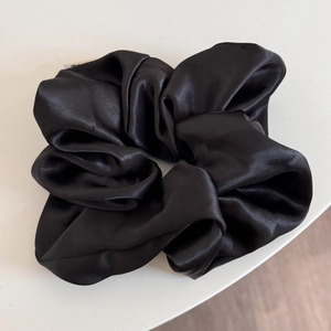 Detailed view of a black oversized satin scrunchie featuring high-gloss silk-like texture