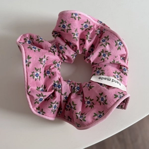 Détail d'un chouchou rose fleuri avec étiquette faite main et motif bleu