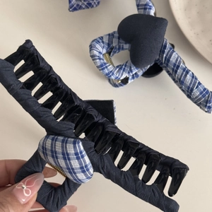 Detail of blue textured fabric and blue-white gingham plaid hair claws with heart accent