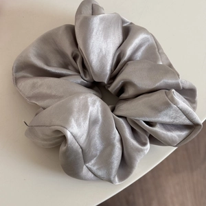 Detailed view of silver grey satin silk scrunchie with soft pleated texture and elegant shine