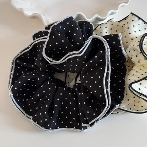 Close-up of black and white polka dot scrunchies with contrasting overlock edges