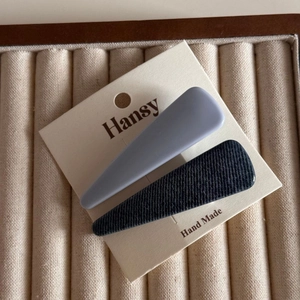 Macro view of denim fabric and matte grey hair clips on an artisan display card