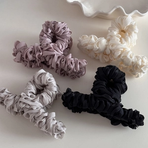 Detail view showing four pleated satin hair claws in purple, beige, silver, and black silk