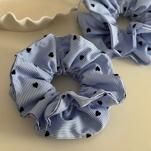 Détail de chouchous à rayures bleues et motifs cœurs noirs sur fond minimaliste