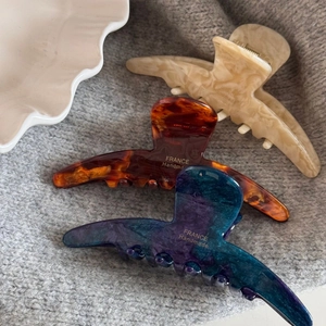 Three premium acetate claw clips in marble, tortoiseshell, and starry purple finishes