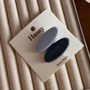 Close-up of matte grey and denim textured oval hair clips on a handmade display card