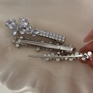 Detailed view of silver bow hair clip set with sparkling rhinestones and pearl accents