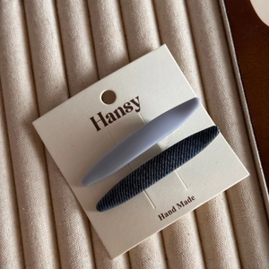 Detail of gray matte and black twill fabric hair clips on a premium handmade display card