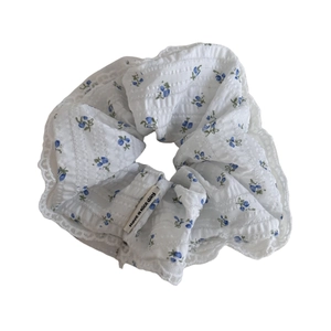 White scrunchie with blue floral print, white lace trim and "have a nice day" label