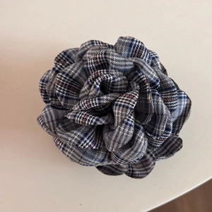 Detailed macro view of British plaid fabric layers on a rose-shaped shark hair clip
