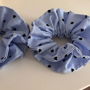 Vue détaillée de deux chouchous à rayures bleues et motifs de cœurs noirs sur blanc